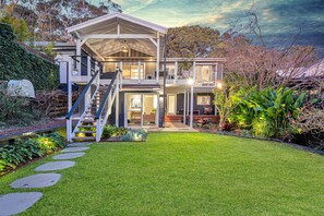 Stunning two-story home with a spacious front yard and a prominent staircase leading to a balcony.