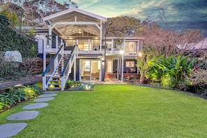 Stunning two-story home with a spacious front yard and a prominent staircase leading to a balcony.