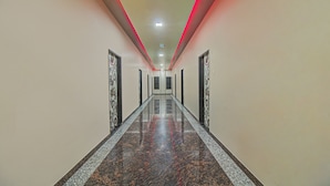 A long, narrow hallway with a polished marble floor and a red accent lighting strip on the ceiling. - Treebo Royal, Chandrapur (Chandrapur)