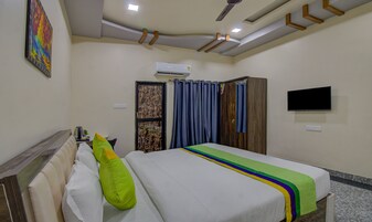 Habitación de hotel con cama, televisión, aire acondicionado y ventana con cortinas.