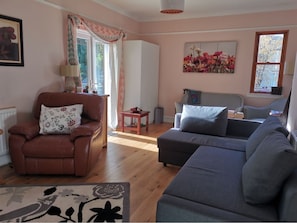 Relax in this inviting living room with a leather armchair, sofa, and a view of the surrounding trees.
