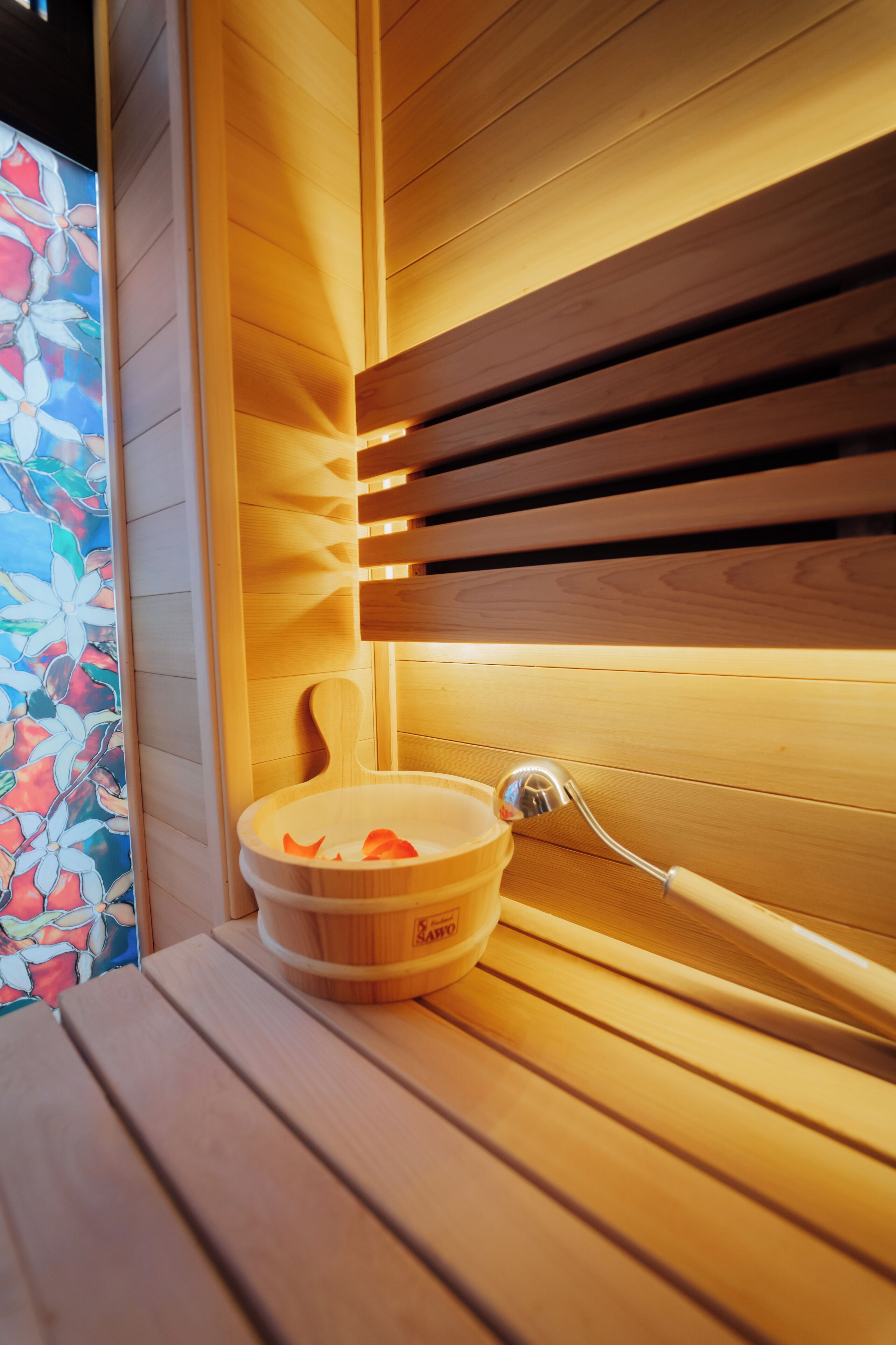 A wooden bench with a wooden bowl and a metal lamp.
