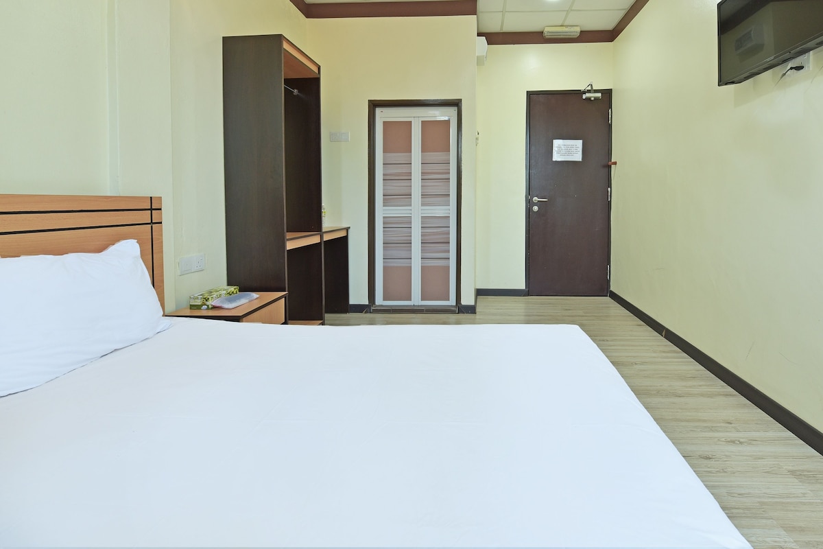 Una habitación de hotel con una cama, un armario, una puerta y un televisor montado en la pared.