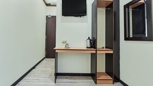 Een gang met een houten bureau, een aan de muur bevestigde televisie en een deur.