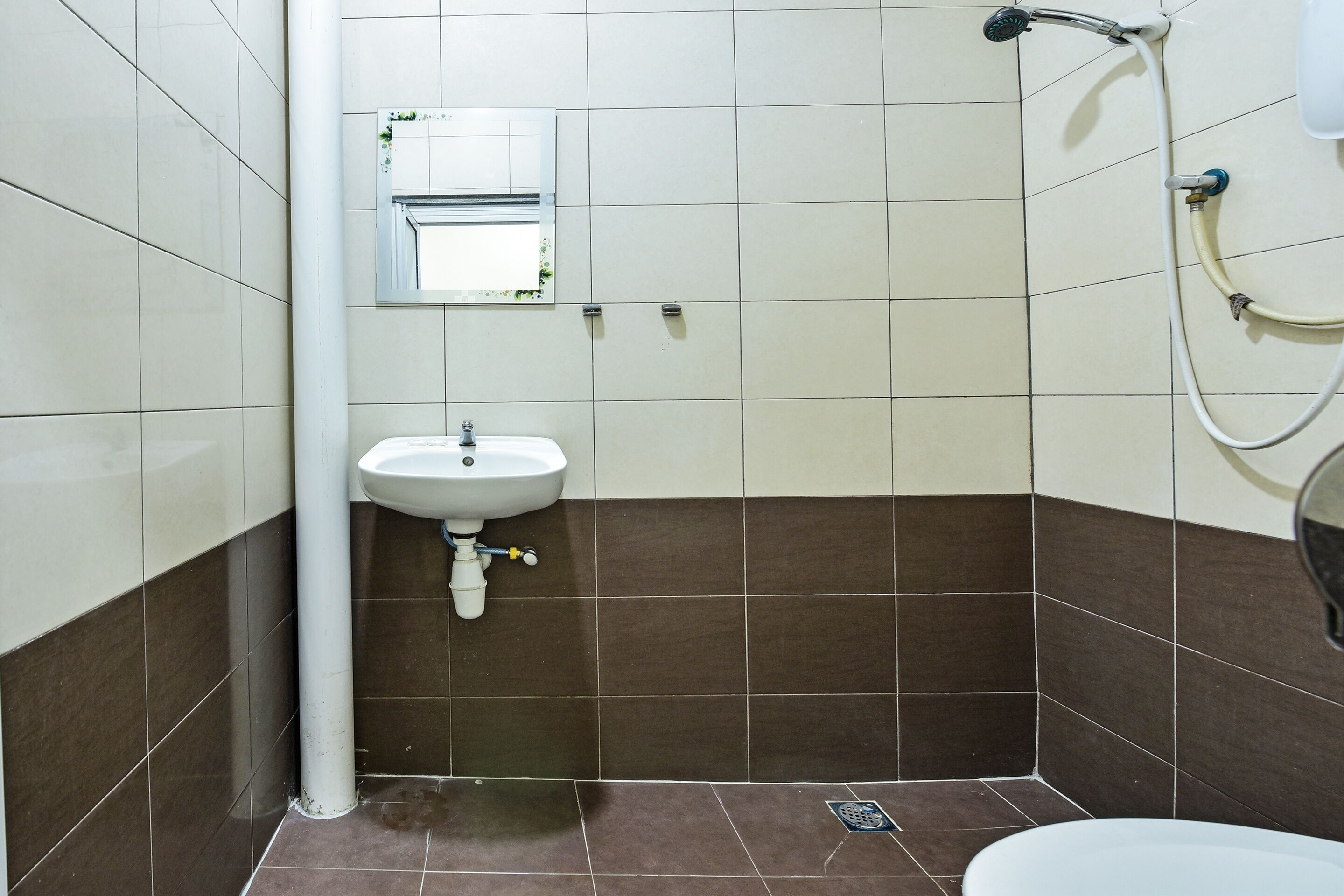 A bathroom with a sink, mirror, shower, and tiled walls.
