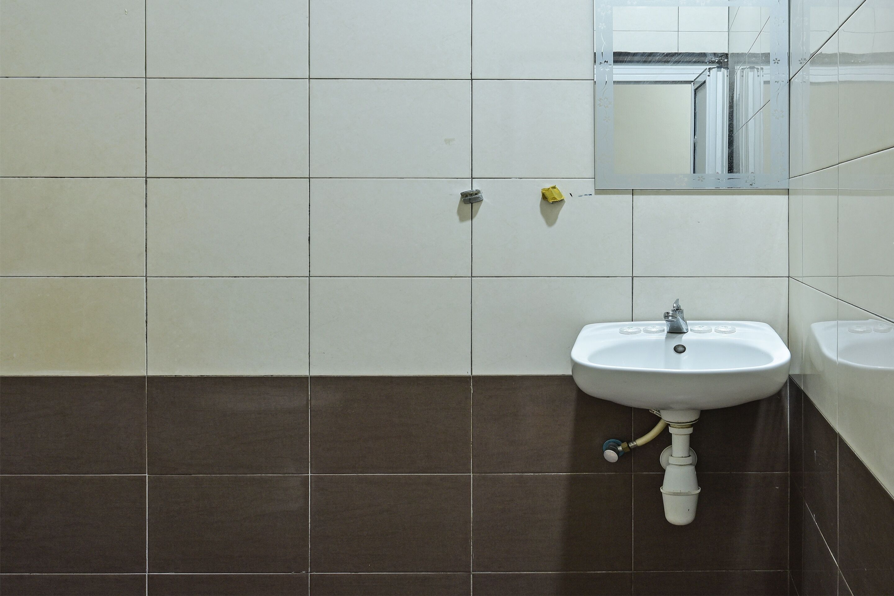 Un baño con lavamanos blanco, un espejo y azulejos marrones.