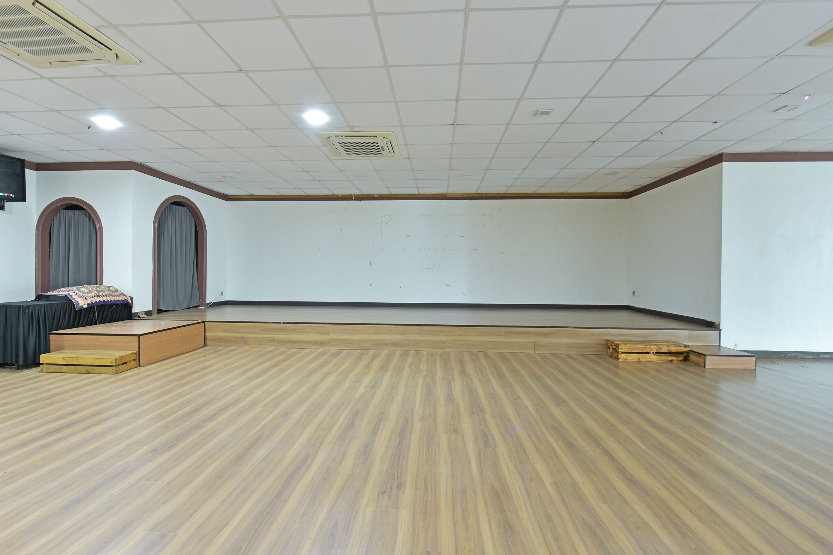 Une pièce spacieuse dotée d’un plancher en bois, d’une scène et d ’un téléviseur à écran plat fixé au mur.