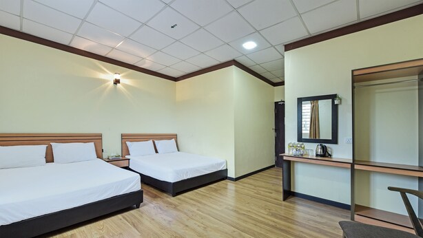 Een hotelkamer met twee bedden, een bureau met spiegel en een stoel.