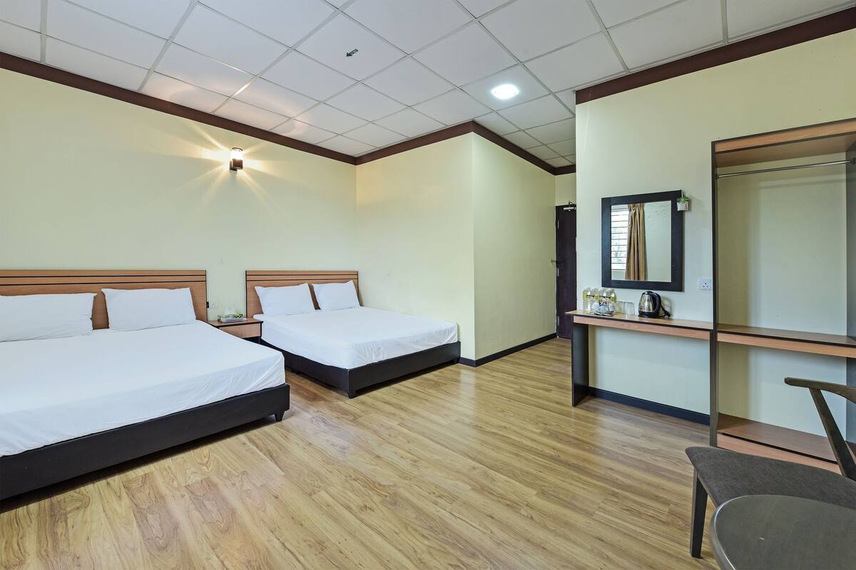 Een hotelkamer met twee bedden, een bureau met spiegel en een stoel.