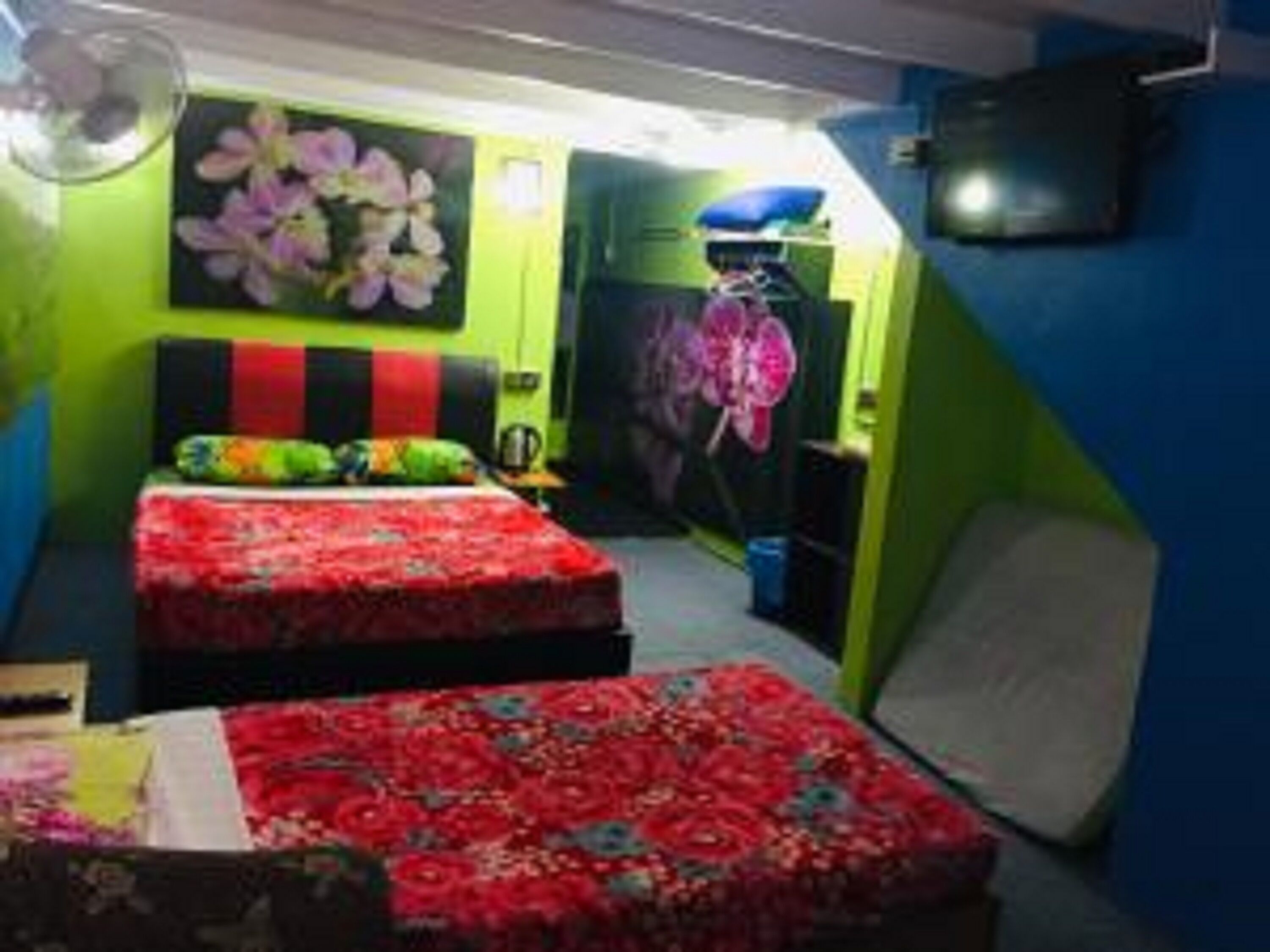 A room with two beds, a green wall, and a pink flower decoration.