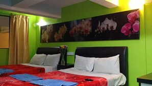 Una camera d'albergo con una parete verde, un grande quadro floreale, un letto con biancheria bianca e rossa e un comodino con una lampada.