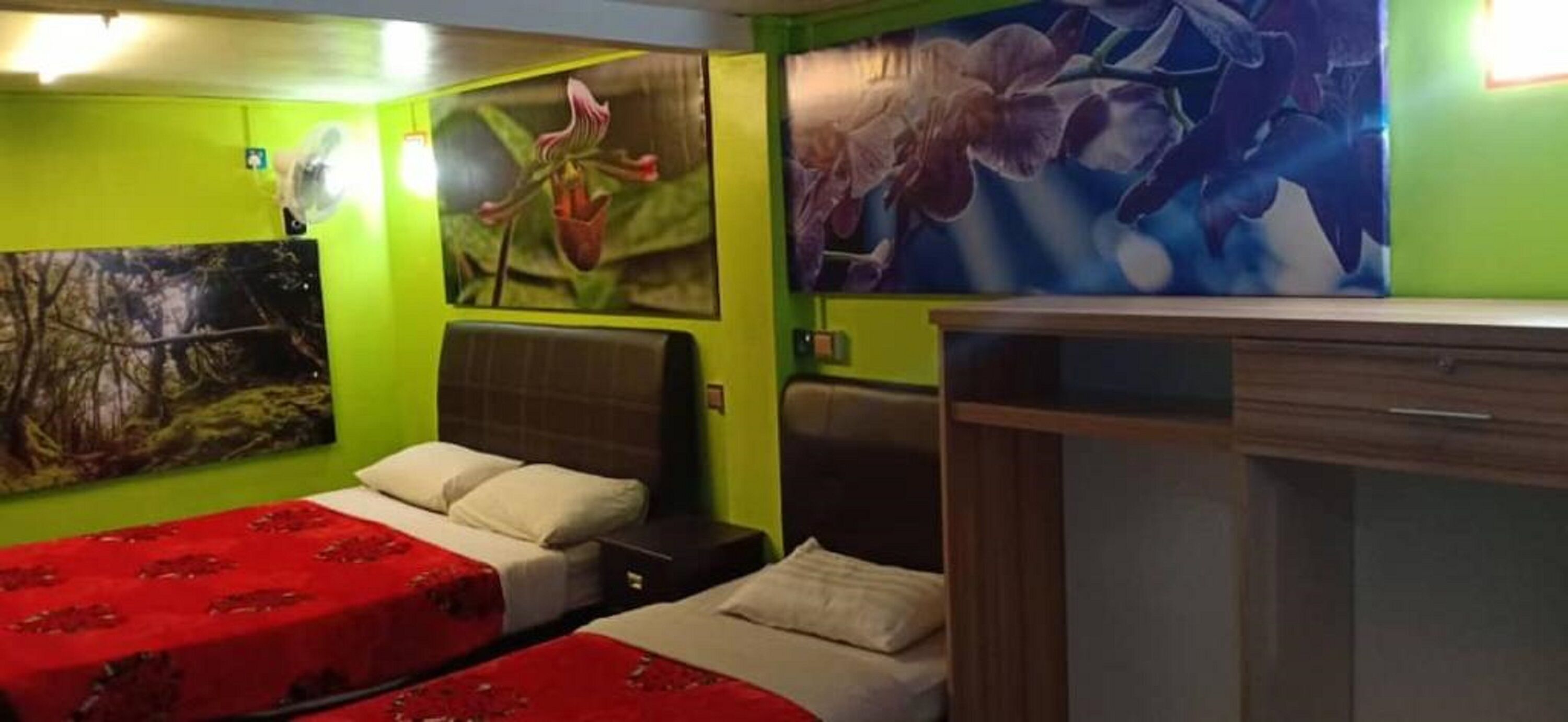 A room with two beds, a wooden cabinet, and floral wall art.