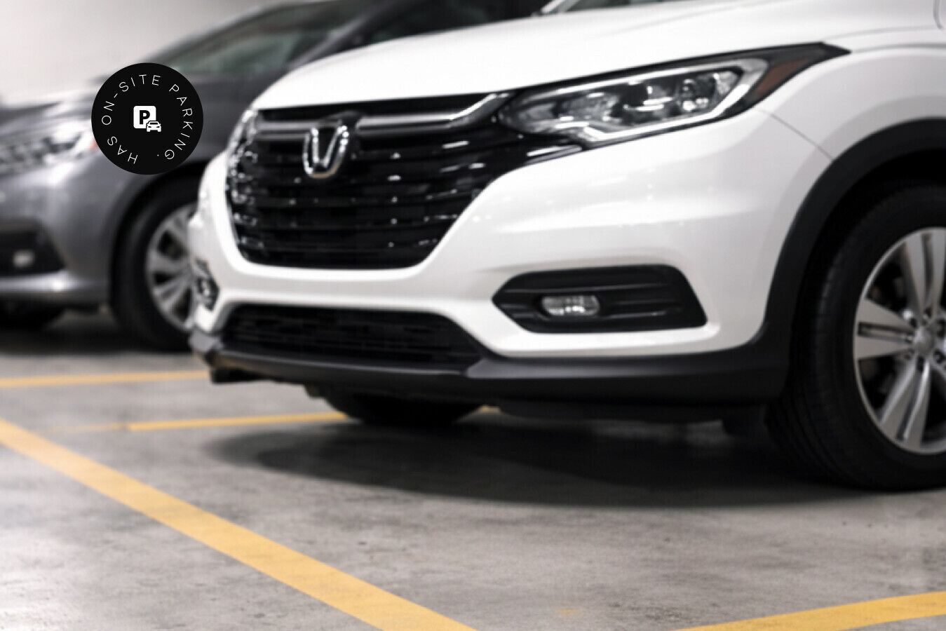 Um SUV branco estacionado em uma garagem com uma placa de estacionamento visível.