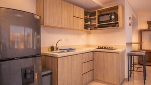 Una cocina compacta equipada con un refrigerador integrado, un microondas y una estufa a gas.