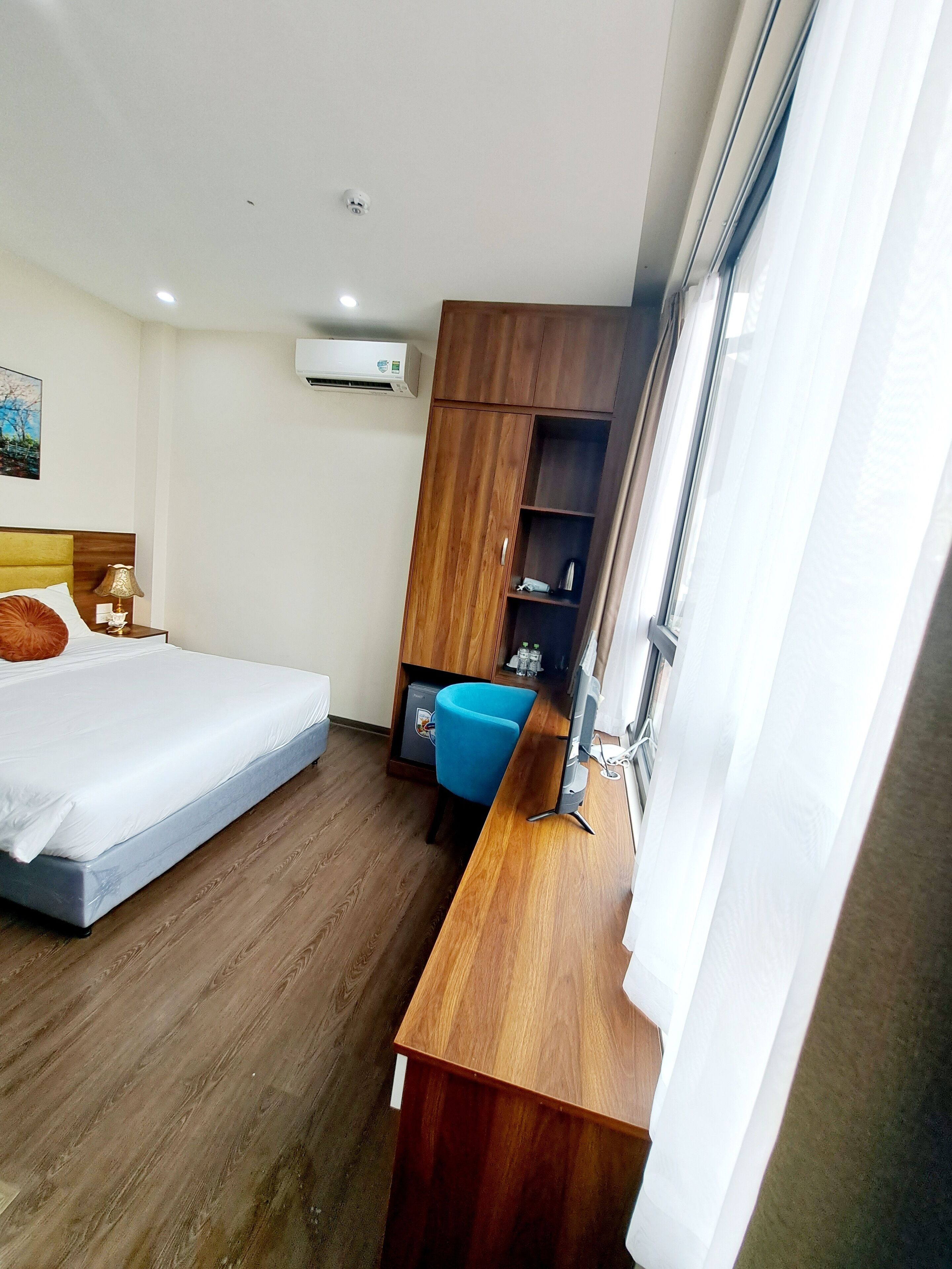 A hotel room with a bed, a desk with a computer, a wardrobe, and a window.