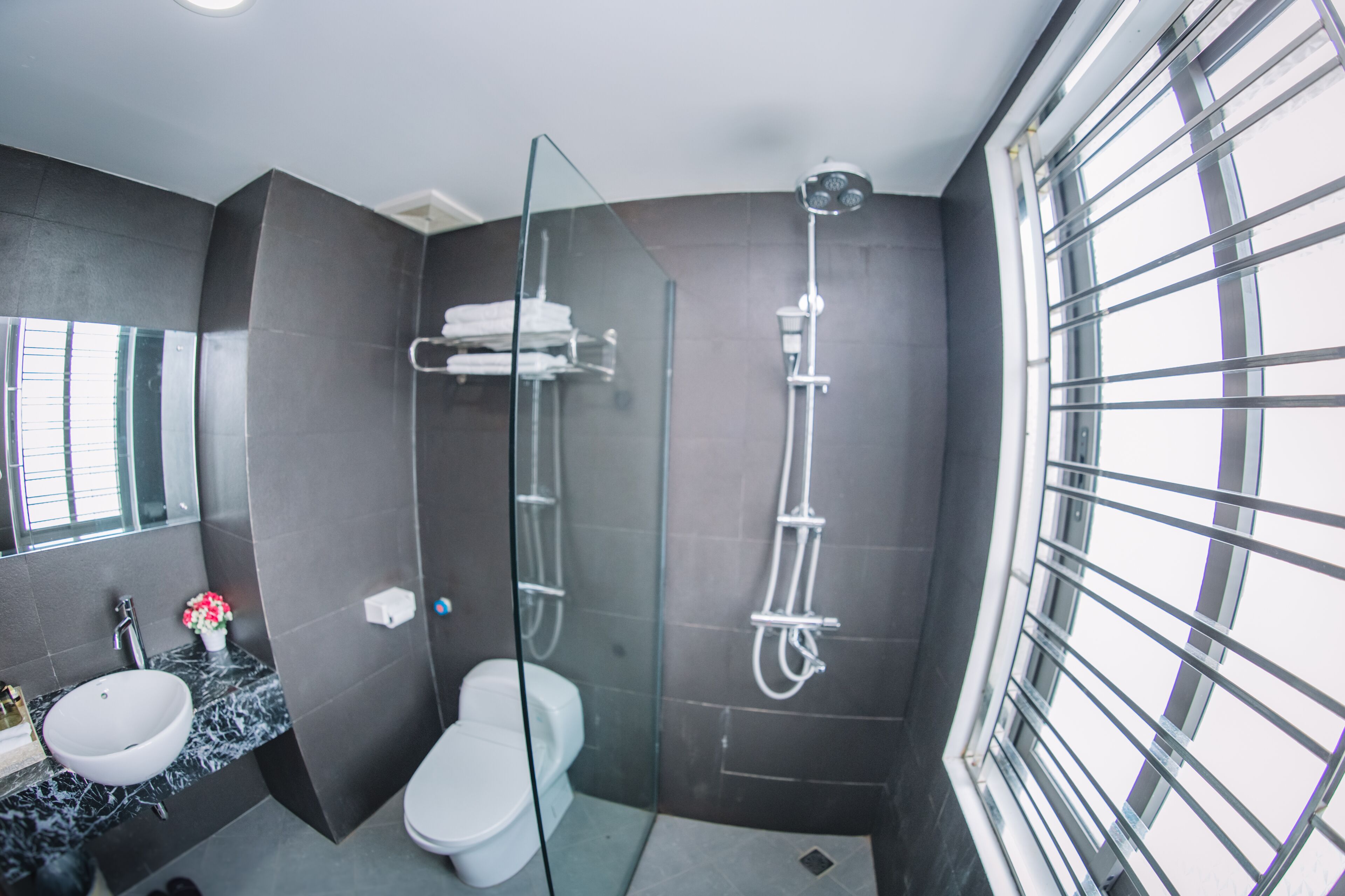 A modern bathroom with a glass-enclosed shower, a white toilet, and a marble sink.