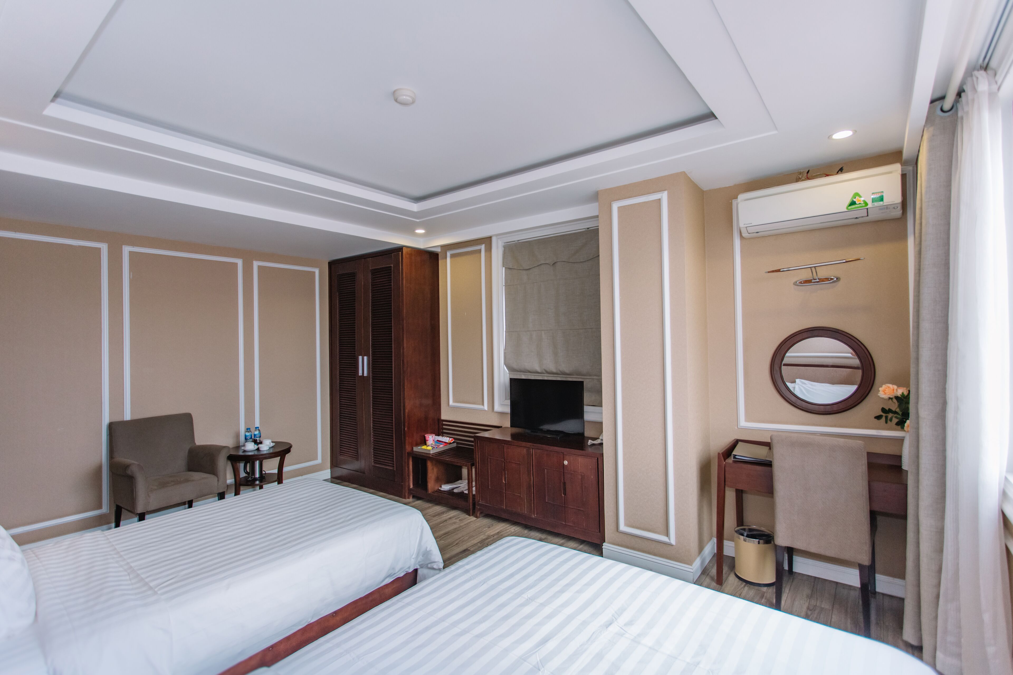 A hotel room with two beds, a desk, a chair, a TV, and a wardrobe.