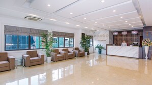 A hotel reception area with a marble counter, beige sofas, potted plants, and large windows. - Cao Minh Hotel Lao Cai (Lao Cai)