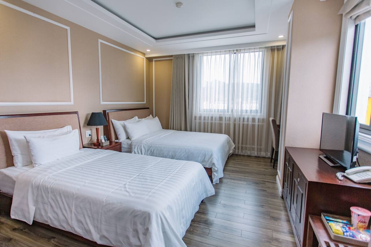 Una habitación de hotel con dos camas, un escritorio con computadora y televisión.