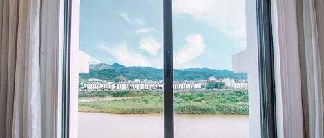 A window with a view of a river, buildings, and mountains.