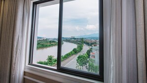 A window with a view of a river, buildings, and greenery. - Cao Minh Hotel Lao Cai (Lao Cai)
