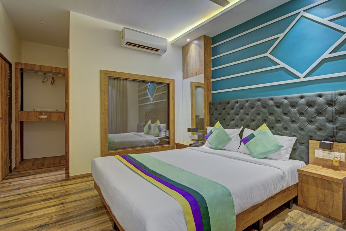 Habitación de hotel con una cama grande, un armario de madera, un espejo y un aire acondicionado de pared.