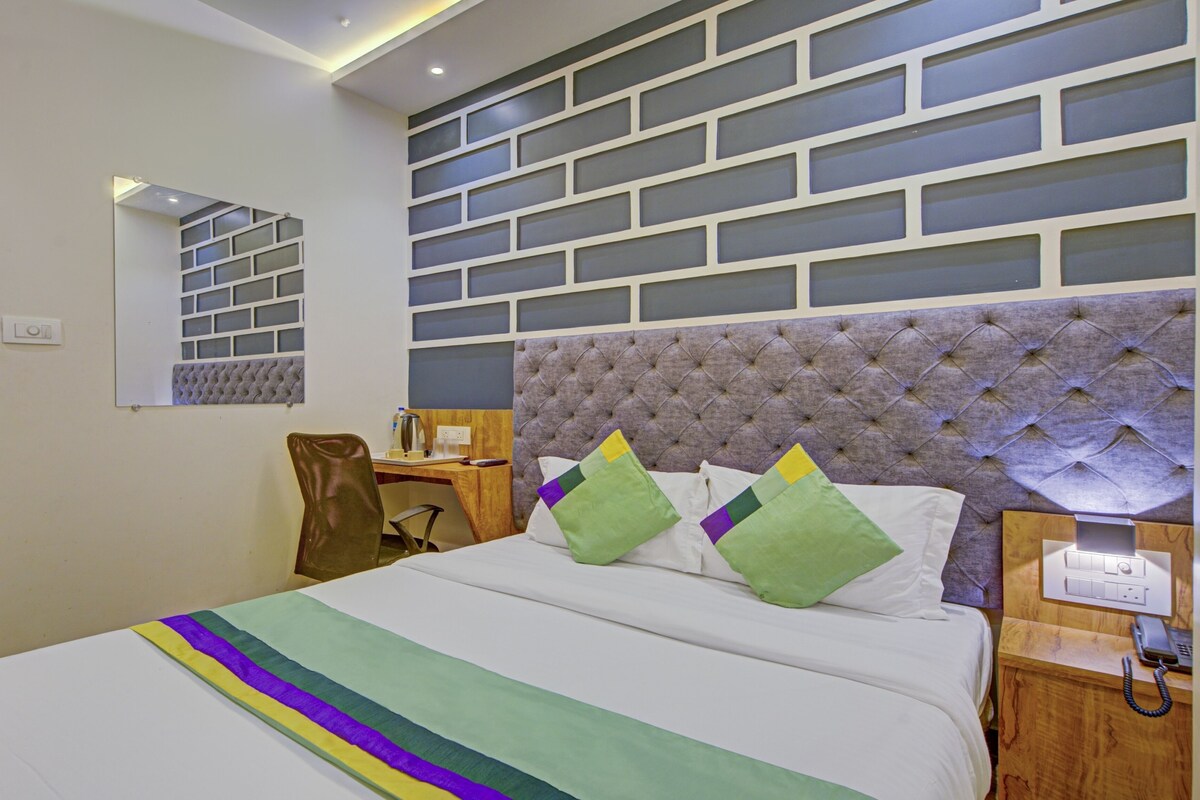 Una habitación de hotel con una cama, un escritorio, una silla, un espejo y una pared con diseño de ladrillo.