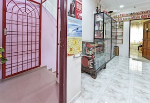 A hallway with a glass display case containing various items, a red metal gate, and a wall with a poster.