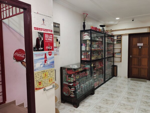 Un couloir avec une vitrine contenant divers objets, une affiche de Coca-Cola et une porte sur laquelle est apposée une pancarte.