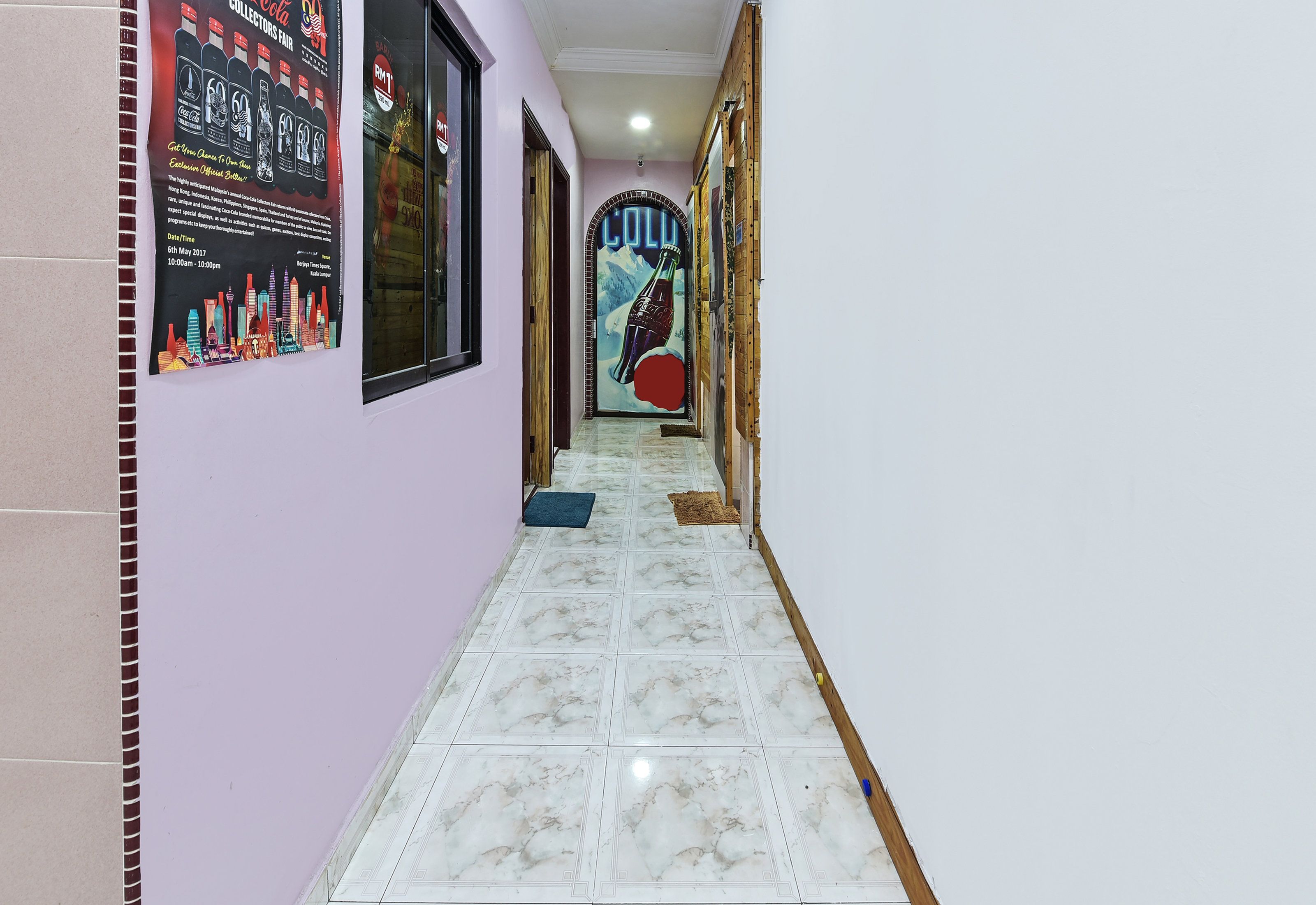 Un pasillo con piso de baldosas, un cartel en la pared y una puerta con panel de vidrio.