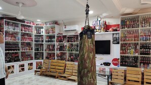 A spacious room with tiled flooring, wooden benches, and shelves stocked with various beverages. - Hotel O Coke Guest House (Alor Gajah)
