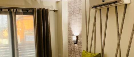 Une chambre d’hôtel équipée d’un lit, de rideaux, d’un appareil de climatisation et d’un luminaire fixé au mur.