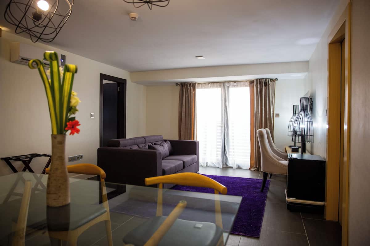 A living room with a sofa, a glass table, and a purple rug.