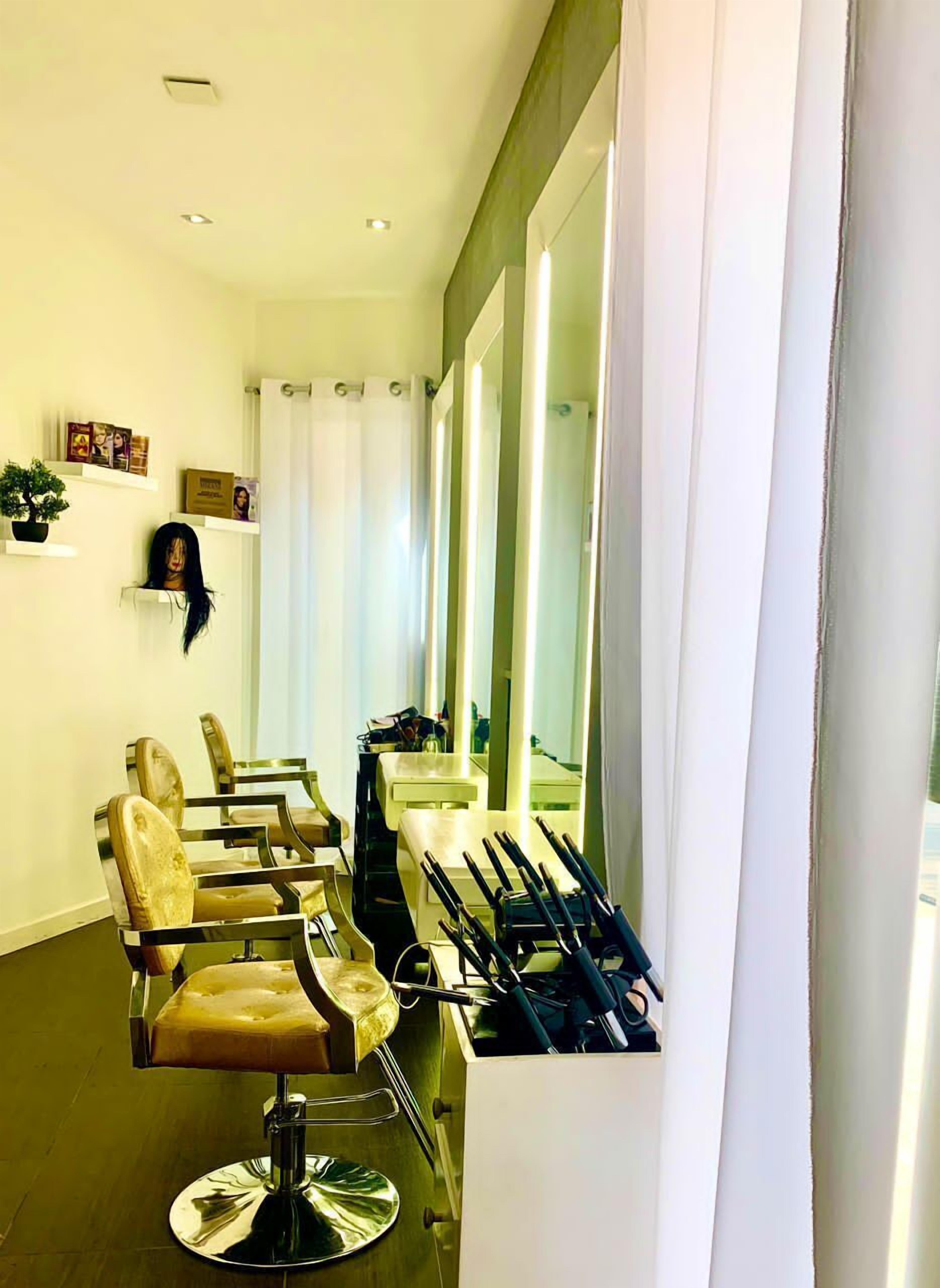 Un salon équipé de plusieurs fauteuils, de miroirs et d’étagères où sont présentés les produits.