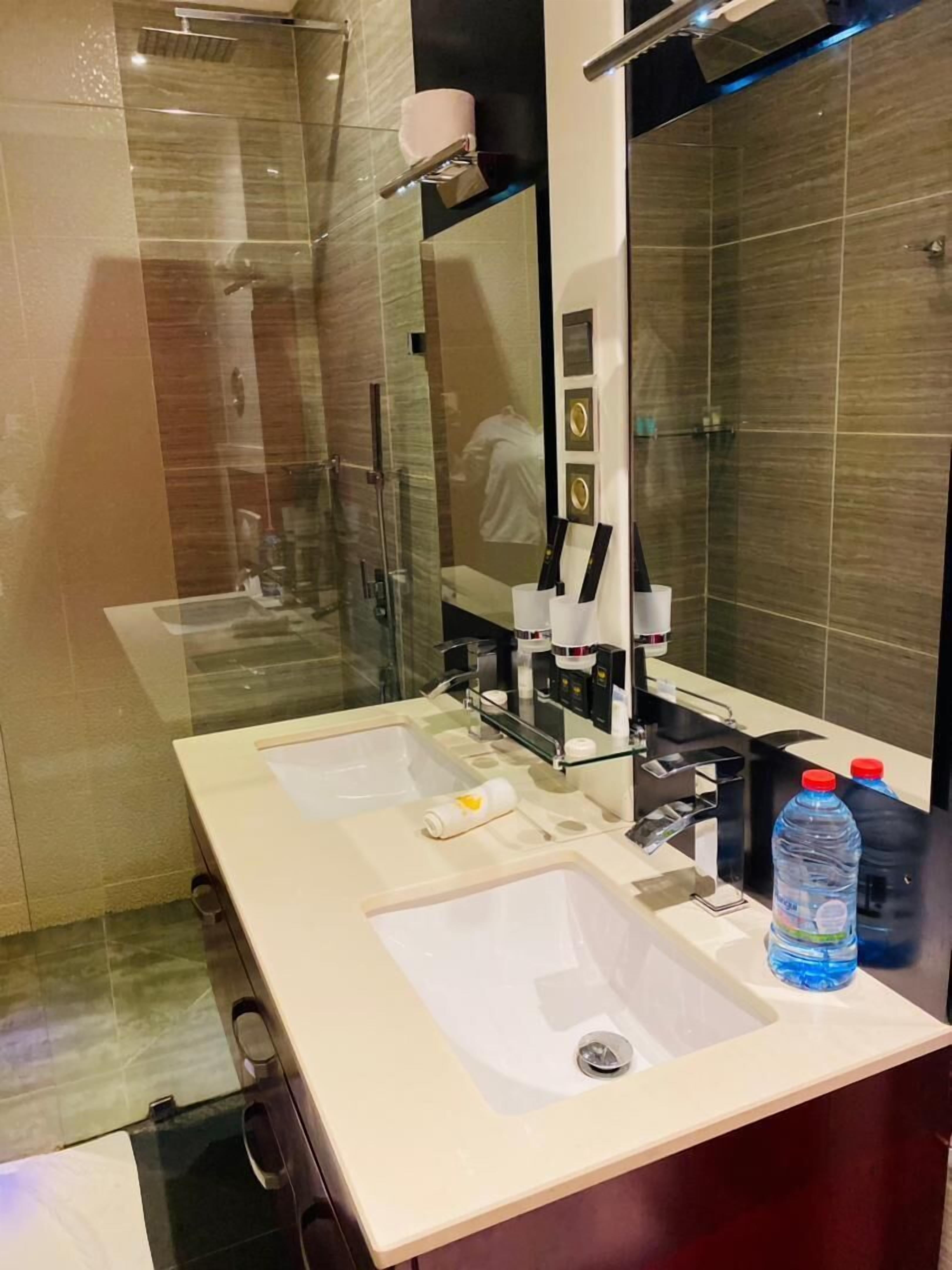 A modern bathroom with two sinks, a large mirror, and a glass shower enclosure.