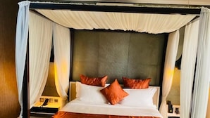 A large bed with a canopy, white bedding, and orange pillows. - Boun's Hotel Resort & Spa (Yaoundé)
