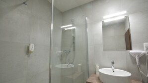 A modern bathroom with a glass-enclosed shower, a wooden vanity with a sink, and a mirror above the sink. - Adeba Plus (Prague)