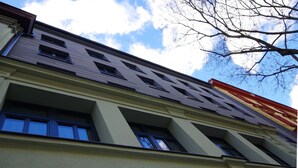 A building with a modern architectural design, featuring a series of windows and a prominent red and yellow sign on the upper right side. - Adeba Plus (Prague)