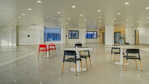 Una amplia sala de reuniones, bien iluminada, con varias mesas y sillas, ventanas grandes y un diseño moderno.