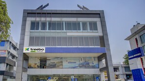 Un edificio moderno con un letrero que dice 'Treebo' en la planta baja, indicando un banco o servicio financiero.
