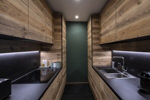 Een moderne keuken met houten kastjes, een zwart aanrecht en een groene accentmuur.