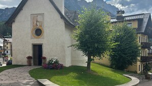 A church with a bell tower, surrounded by a stone wall and a paved courtyard.