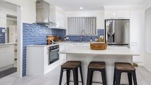 Cozinha moderna com ilha central, eletrodomésticos de aço inoxidável e backsplash revestido em azulejos azuis.