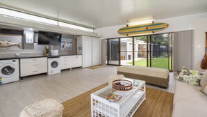 Eine moderne Küche mit integrierten Geräten, ein Essbereich mit Glastisch und eine große Schiebeglas-Tür zum Garten.