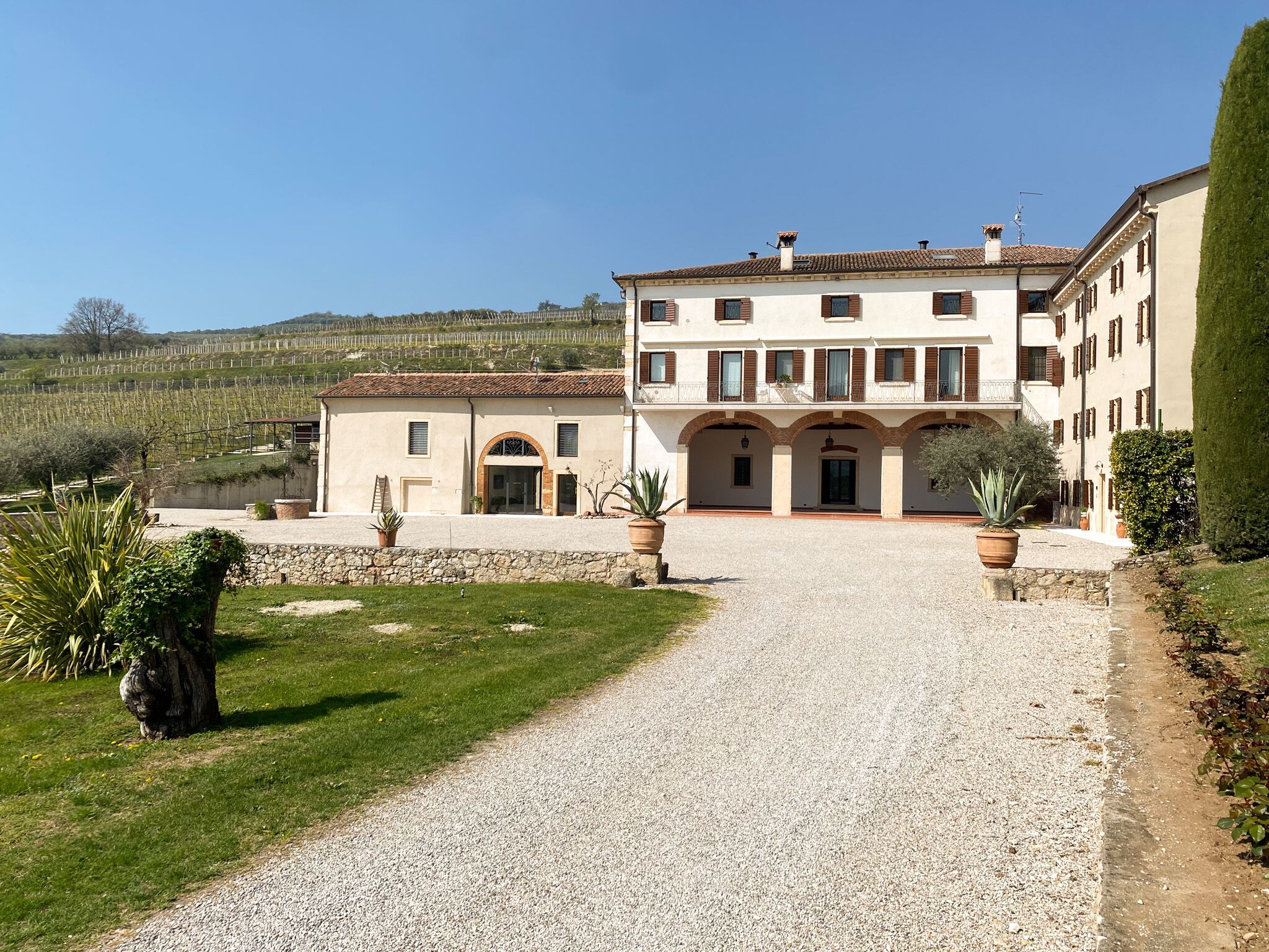 A large building with a gravel driveway leading to a gated entrance.