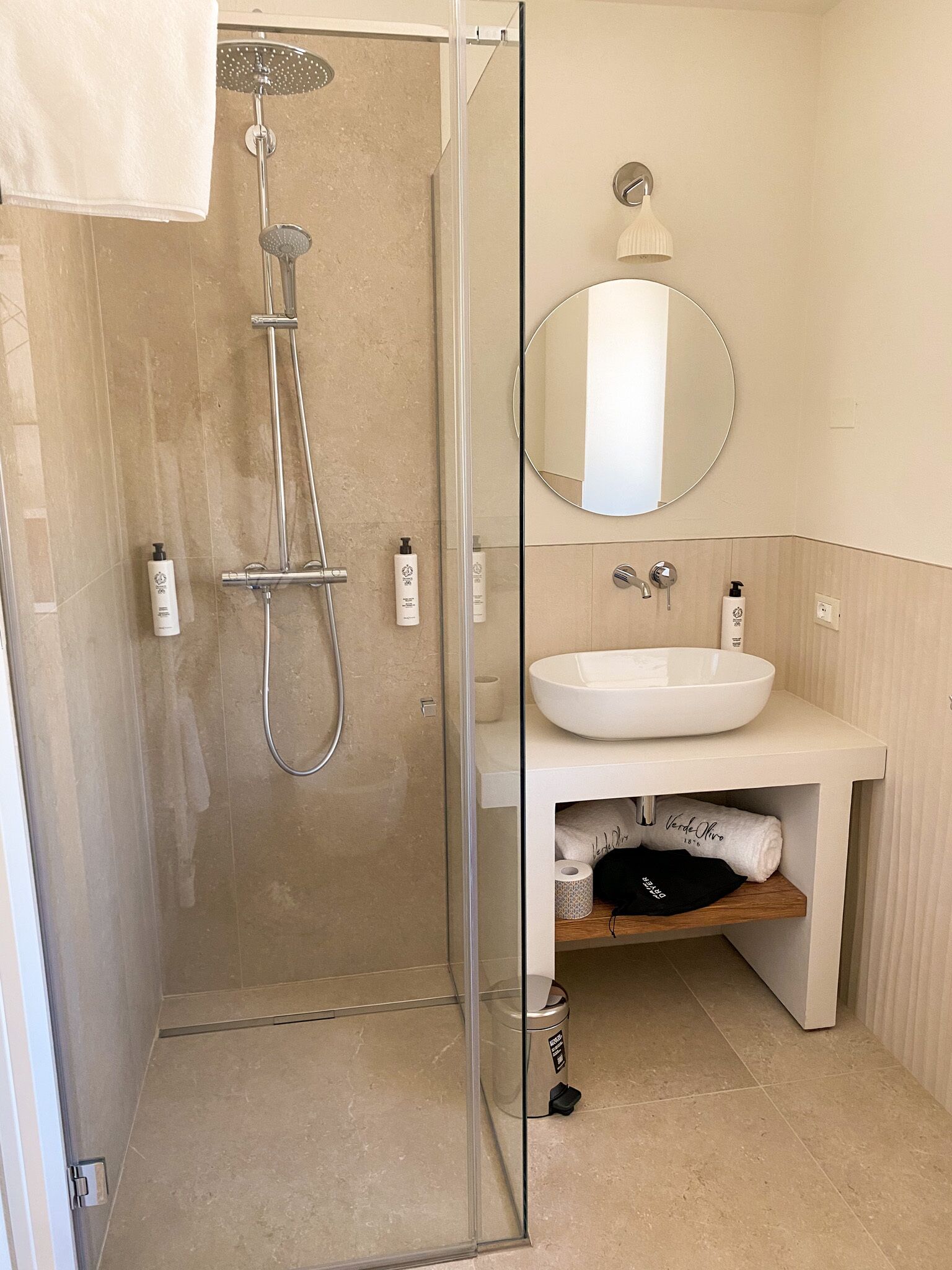 Ein modernes Badezimmer mit einer gläsernen Dusche, einem weißen Waschbecken und einem Spiegel darüber.