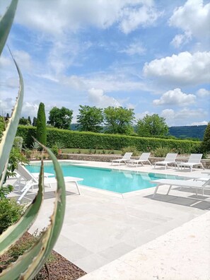 A swimming pool with lounge chairs, surrounded by greenery and a view of the landscape. - VerdeOlivo1876 - Apartments with Pool (Mezzane di Sotto)