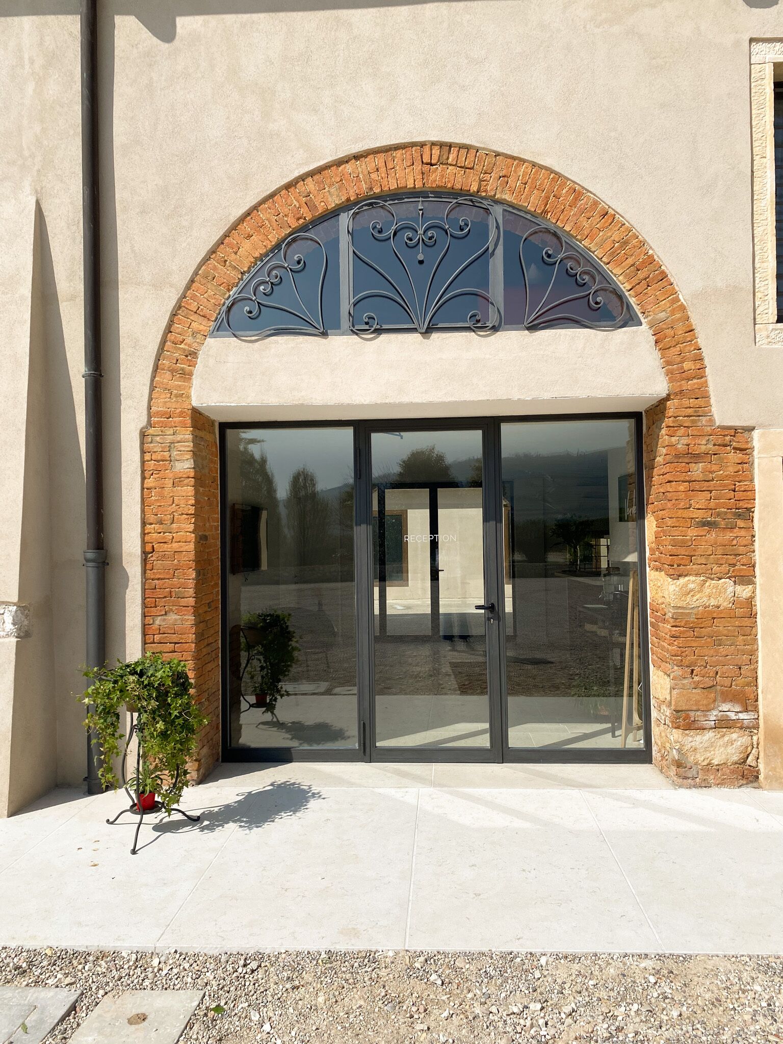 A reception area with a glass door, brick arch, and metal decorative elements.