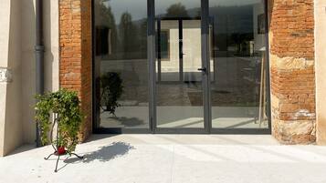 A reception area with a glass door, brick arch, and metal decorative elements.