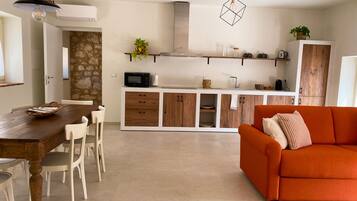 A modern kitchen with white cabinets, a microwave, and a hanging light fixture.
